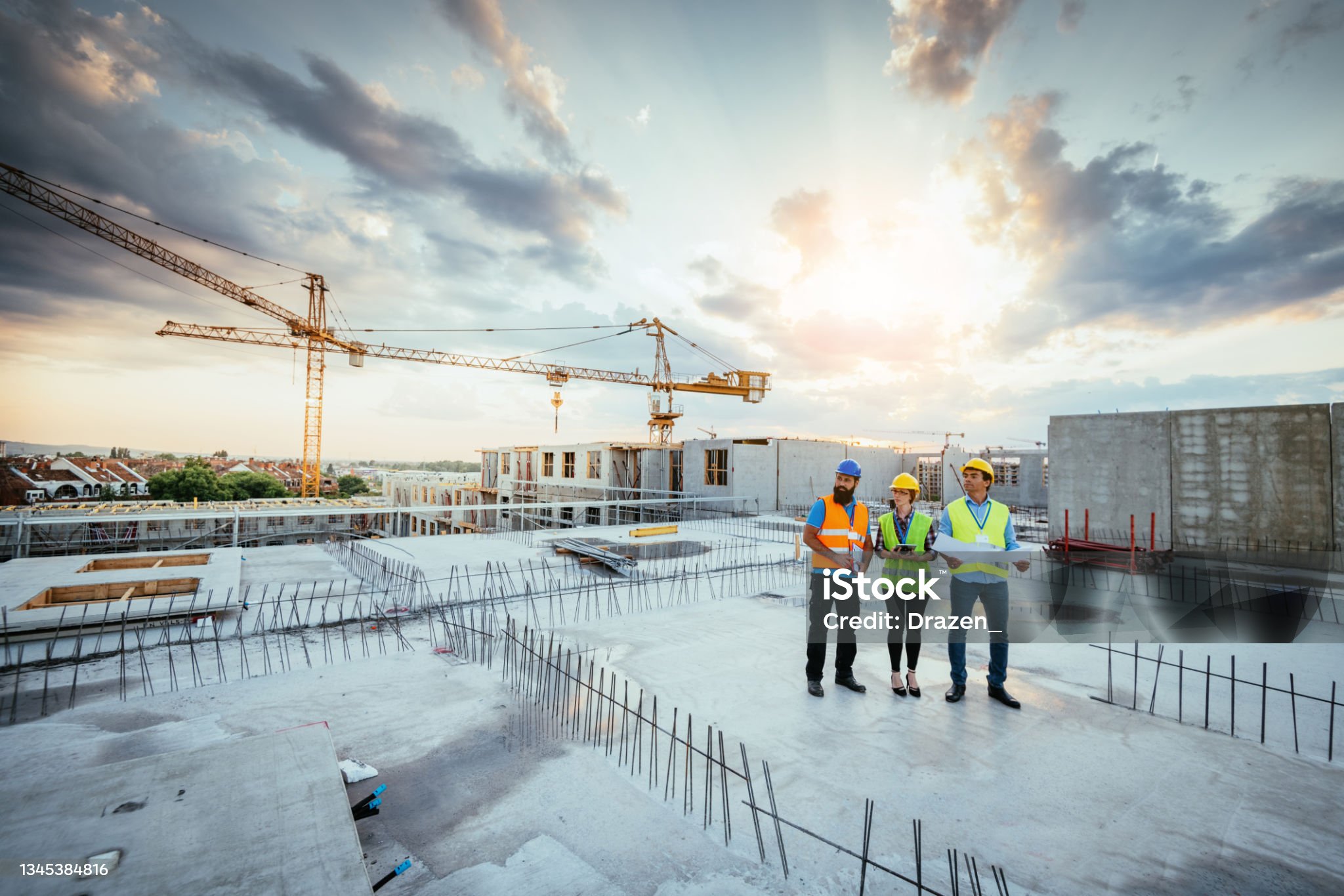 Employees working on construction site, wearing protective equipment and discussing next construction phase